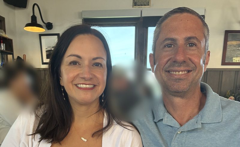 Scott and Tiffany smiling side by side at a waterfront lunch spot.